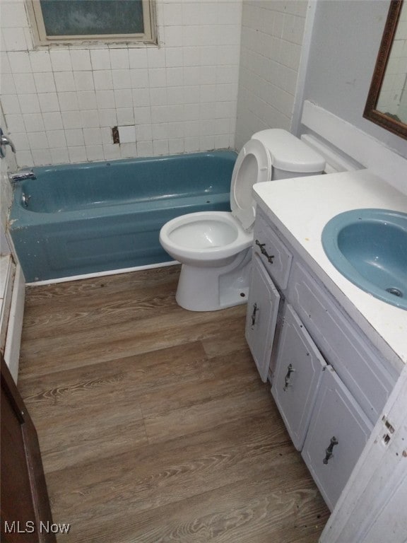 full bathroom featuring hardwood / wood-style flooring, vanity, tiled shower / bath, and toilet