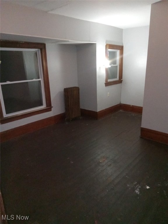 unfurnished room featuring radiator heating unit and dark hardwood / wood-style floors