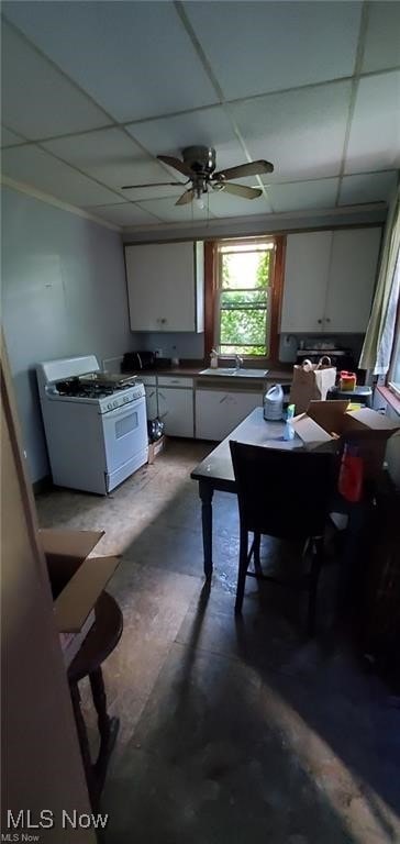 dining space featuring sink, a paneled ceiling, concrete floors, and ceiling fan