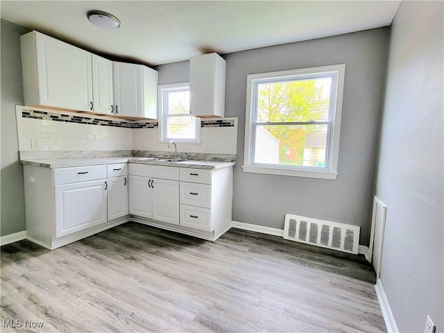 kitchen with white cabinetry, sink, and backsplash