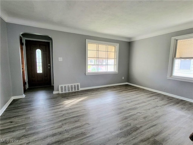 foyer entrance featuring crown molding, dark wood-type flooring, and a healthy amount of sunlight