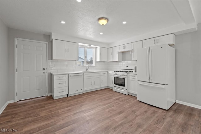 kitchen with white cabinetry, white appliances, light hardwood / wood-style flooring, and decorative backsplash