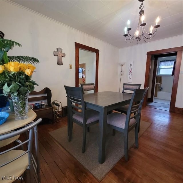 dining area featuring crown molding, dark wood-type flooring, and a notable chandelier