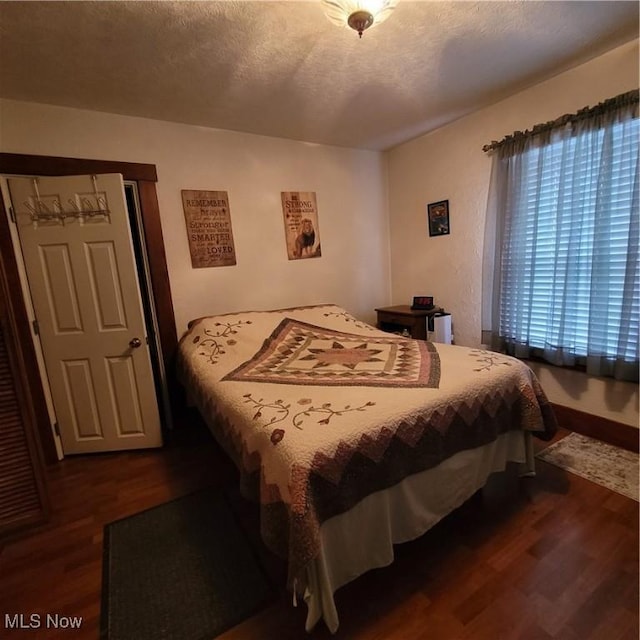 bedroom with dark hardwood / wood-style floors and a textured ceiling