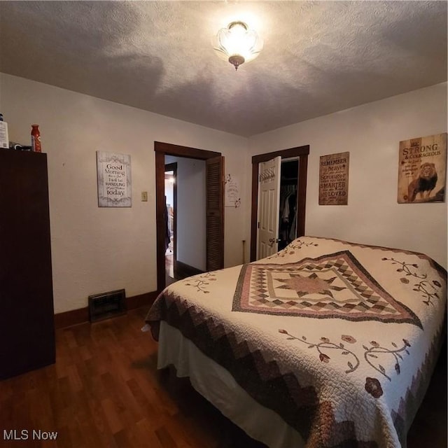 bedroom featuring dark wood-type flooring, a closet, and a textured ceiling