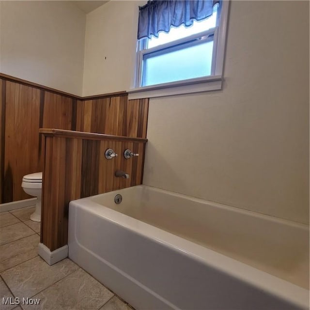 bathroom featuring tile patterned floors, toilet, and a tub