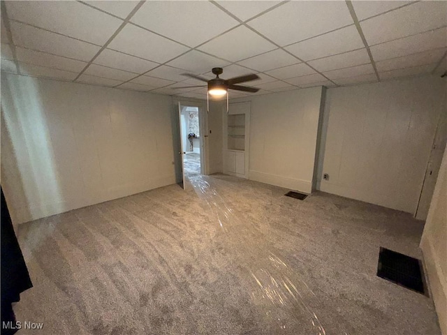 basement with ceiling fan, a paneled ceiling, and light carpet