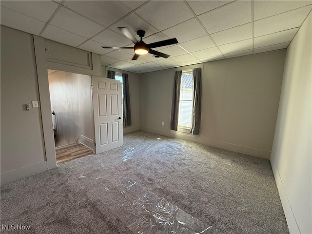 empty room featuring carpet floors, a paneled ceiling, and ceiling fan