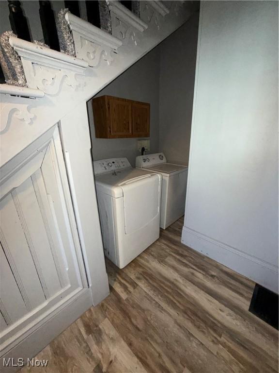 laundry area featuring cabinets, washer and clothes dryer, and light hardwood / wood-style floors