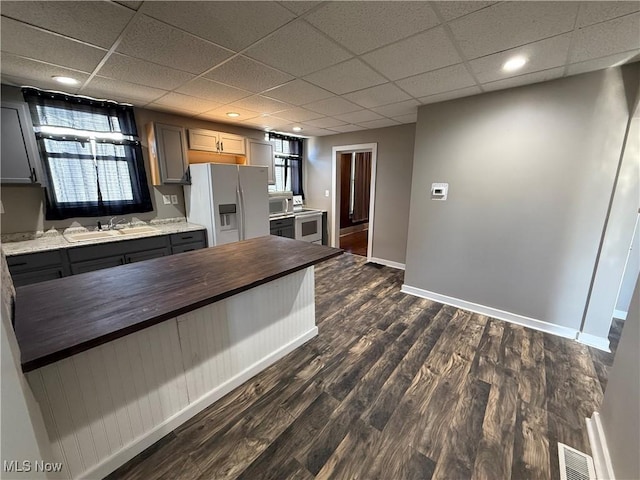 kitchen with wood counters, sink, gray cabinetry, dark hardwood / wood-style flooring, and white fridge with ice dispenser