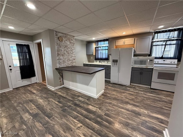 kitchen featuring white appliances, gray cabinets, plenty of natural light, dark hardwood / wood-style floors, and kitchen peninsula