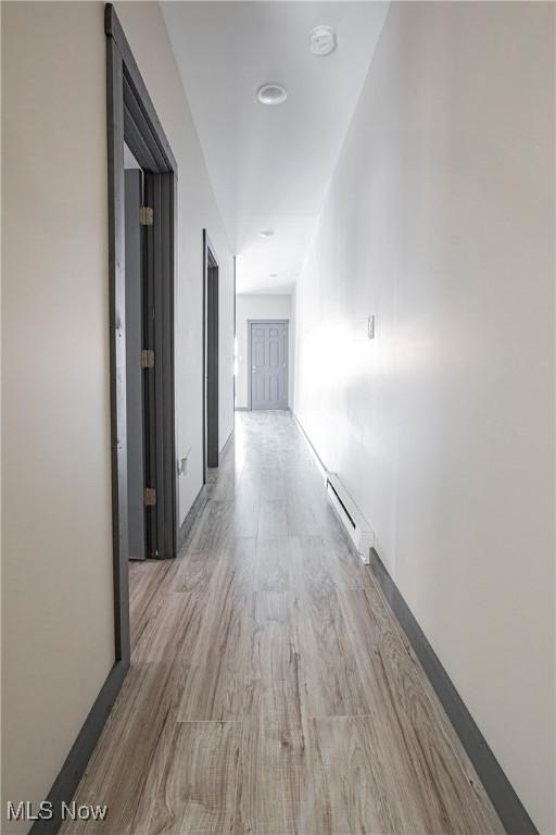 corridor with a baseboard radiator and light wood-type flooring