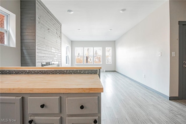 kitchen with butcher block counters, gray cabinetry, and light hardwood / wood-style flooring