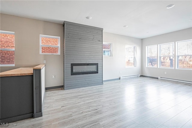 unfurnished living room with a baseboard radiator, a fireplace, and light hardwood / wood-style floors