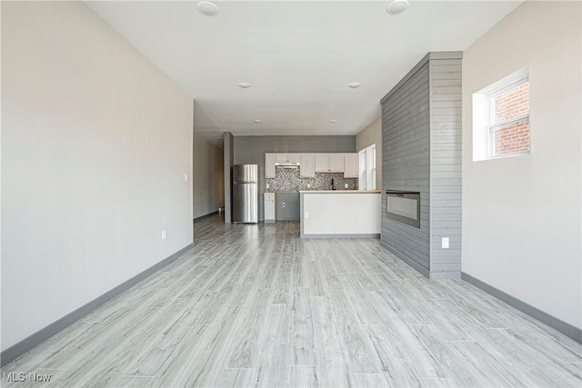 unfurnished living room featuring a fireplace and light hardwood / wood-style floors