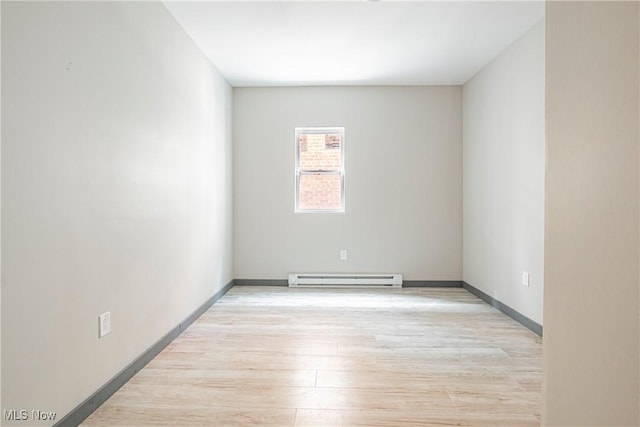 unfurnished room featuring light wood-type flooring and baseboard heating