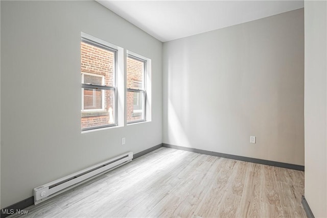 spare room featuring a baseboard heating unit and light hardwood / wood-style floors