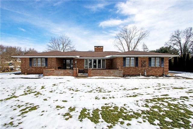 single story home with brick siding and a chimney