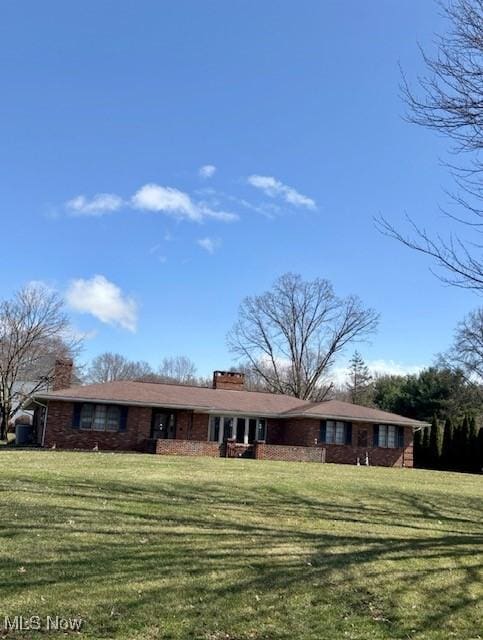 ranch-style home with a chimney and a front yard
