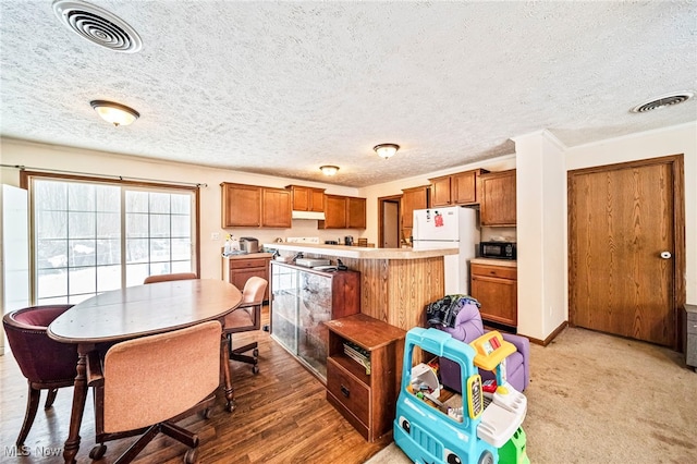 kitchen with crown molding, a kitchen island, white fridge, and a textured ceiling