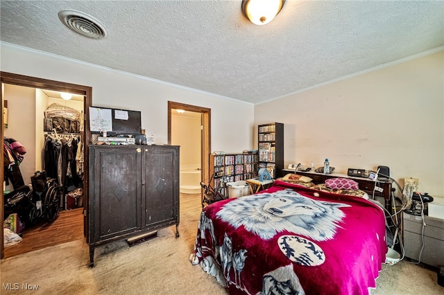 bedroom with crown molding, ensuite bathroom, a textured ceiling, a spacious closet, and a closet