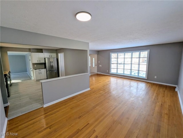 unfurnished living room featuring light hardwood / wood-style flooring and a textured ceiling