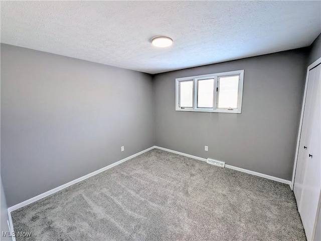 empty room with a textured ceiling and carpet flooring