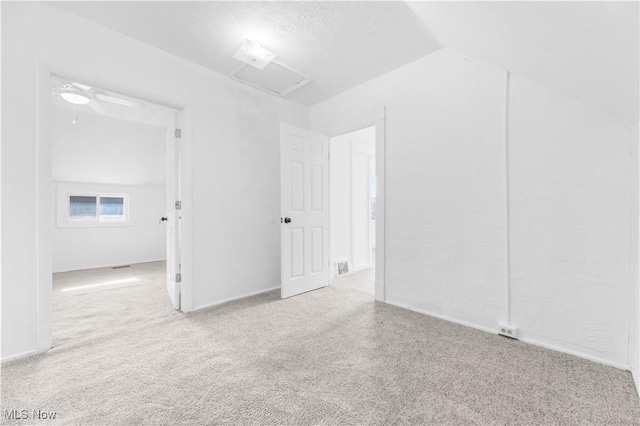 carpeted empty room featuring vaulted ceiling and a textured ceiling