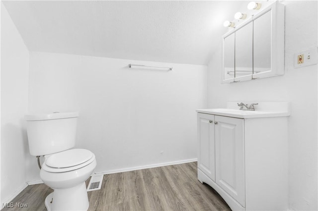 bathroom featuring lofted ceiling, toilet, wood-type flooring, a textured ceiling, and vanity