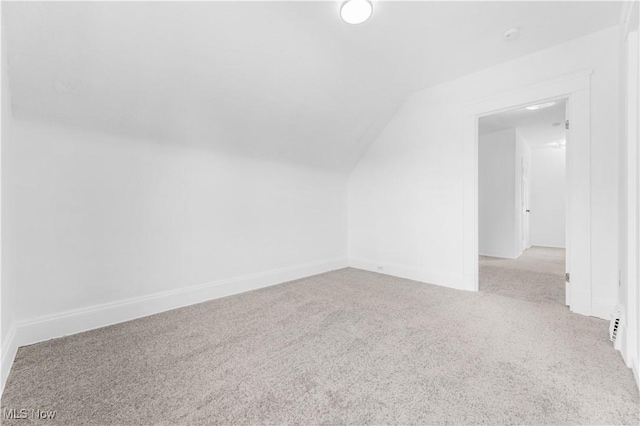 additional living space featuring vaulted ceiling and light carpet