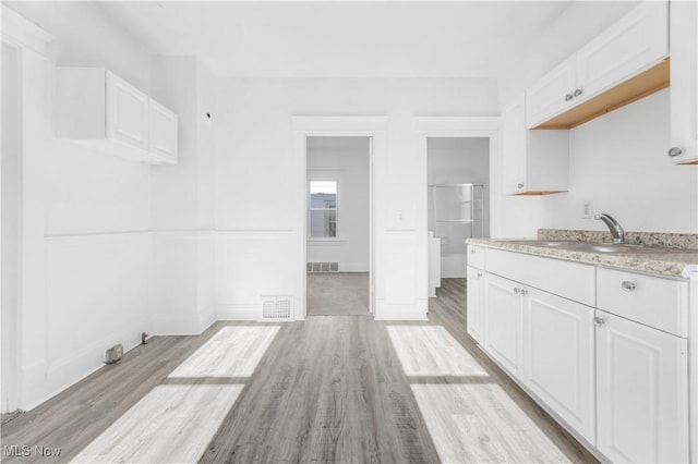 kitchen featuring sink, white cabinets, and light wood-type flooring