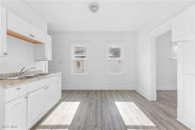 kitchen with white cabinetry, plenty of natural light, sink, and light hardwood / wood-style flooring