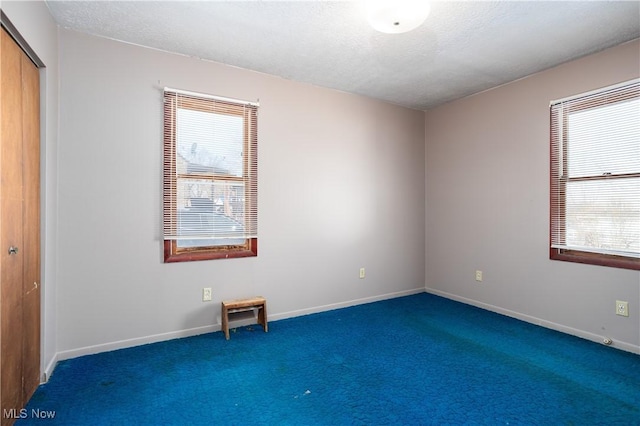 carpeted empty room with a textured ceiling