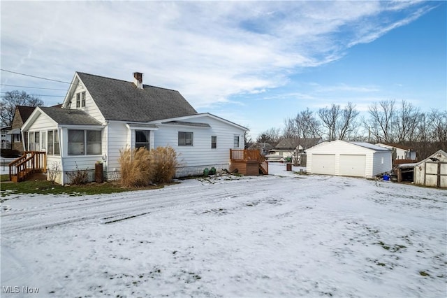 view of snowy exterior with a garage, a sunroom, and a storage unit