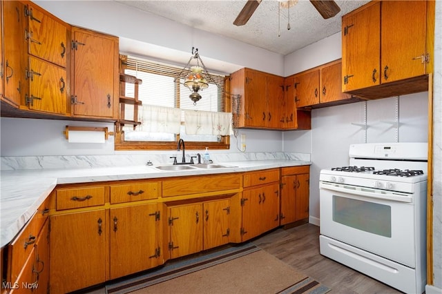 kitchen featuring sink, a textured ceiling, dark hardwood / wood-style floors, white gas range, and ceiling fan