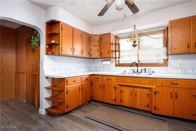 kitchen featuring ceiling fan, sink, dark wood-type flooring, and a textured ceiling