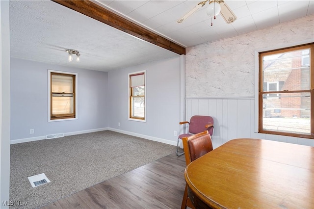 dining area featuring beamed ceiling, wood-type flooring, and a textured ceiling