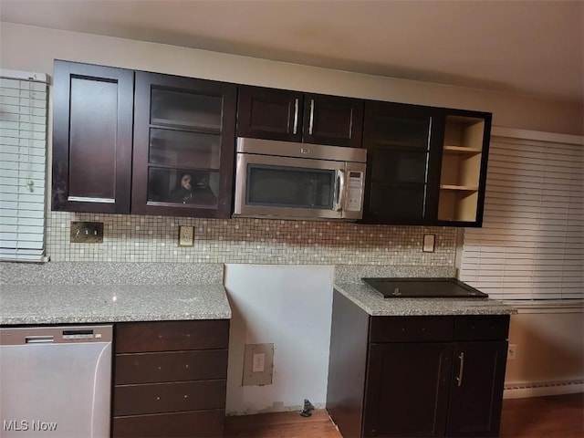 kitchen featuring appliances with stainless steel finishes, dark brown cabinets, light stone counters, and decorative backsplash