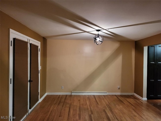 unfurnished dining area with a baseboard radiator and hardwood / wood-style floors