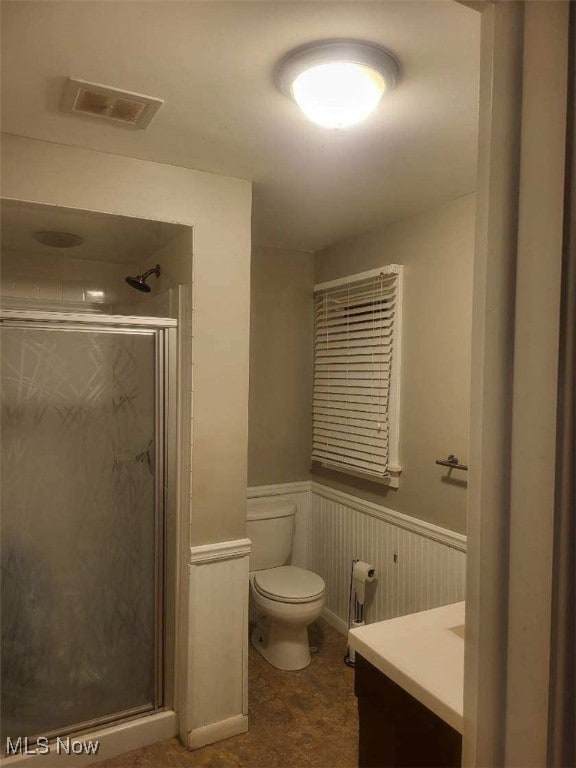 bathroom featuring a shower with door, vanity, and toilet