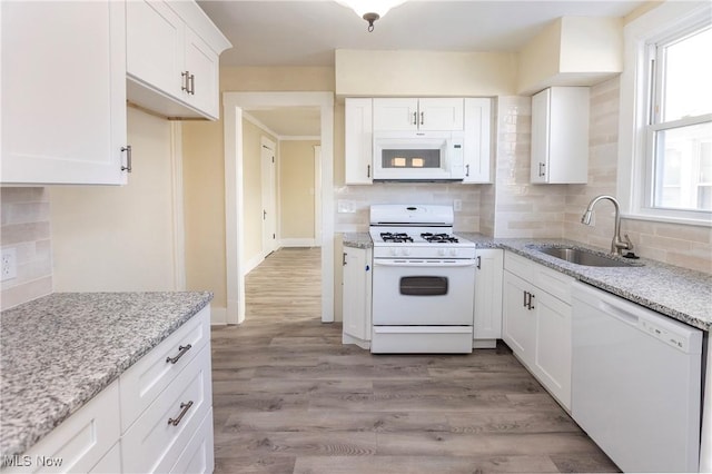 kitchen with sink, light stone counters, white cabinets, and white appliances