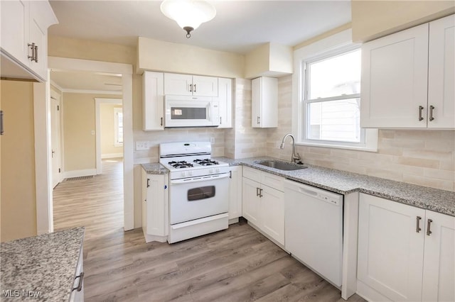 kitchen with white cabinetry, sink, decorative backsplash, light hardwood / wood-style floors, and white appliances