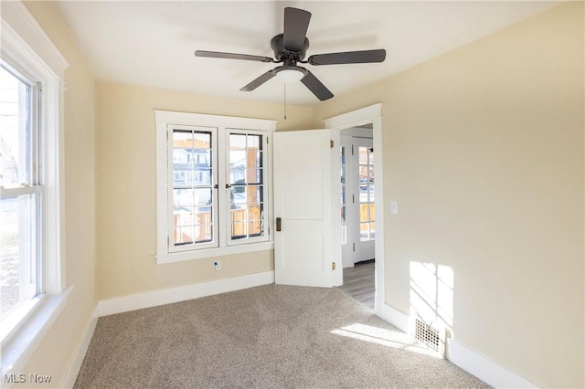 carpeted empty room featuring a wealth of natural light and ceiling fan