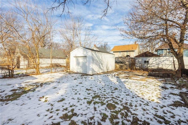 snowy yard featuring a garage and an outdoor structure