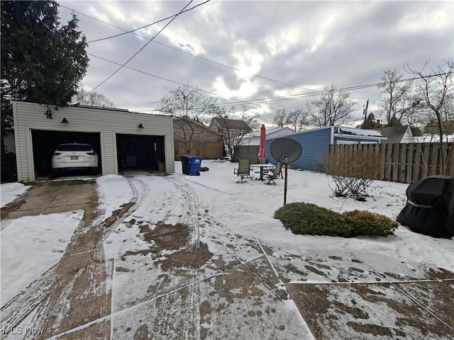 yard covered in snow with a garage and an outdoor structure