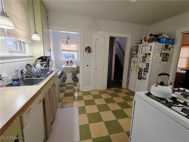 kitchen with pendant lighting, white appliances, sink, and backsplash