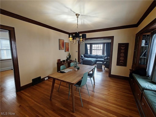 dining space featuring crown molding, a chandelier, and hardwood / wood-style floors