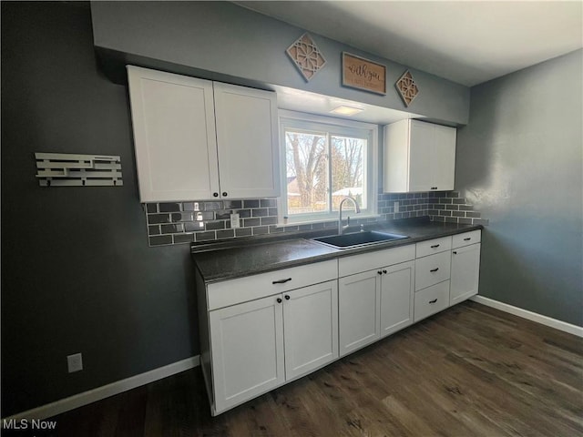 kitchen with tasteful backsplash, sink, white cabinets, and dark hardwood / wood-style flooring