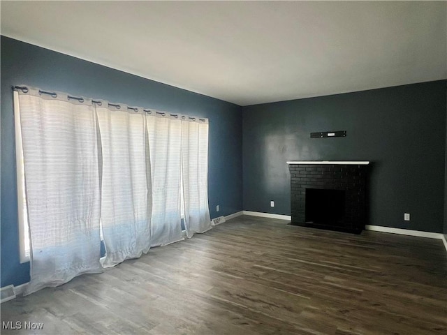 unfurnished living room with dark wood-type flooring and a fireplace