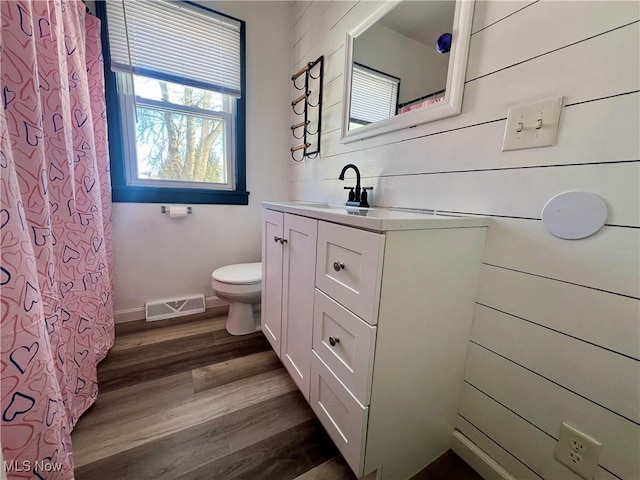 bathroom with vanity, hardwood / wood-style floors, wood walls, and toilet